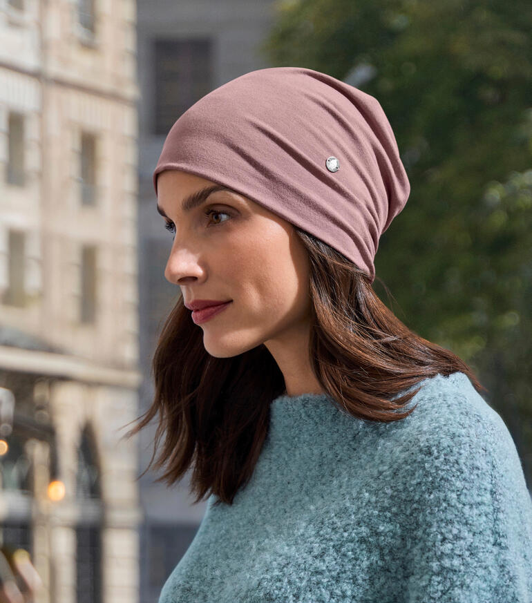 Bamboe beanie in roze, gedragen door een vrouw in een blauwe trui.