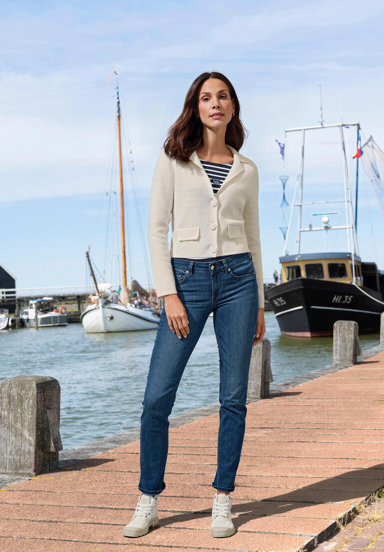 Vrouw in een witte kasjmier blazer aan de haven