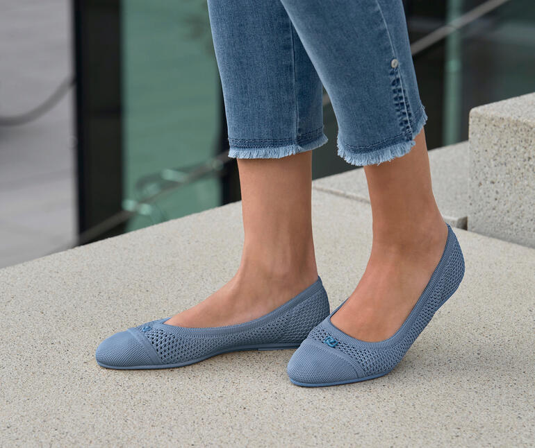 blauw Vrouw draagt blauwe mesh ballerina's, staat buiten op stenen vloer.