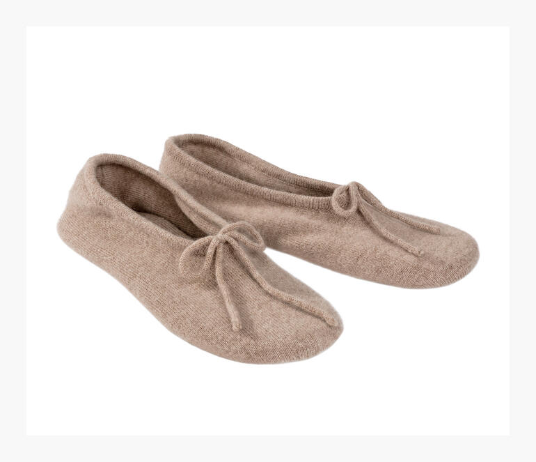 Twee kasjmier reisschoenen in lichtbeige naast elkaar.