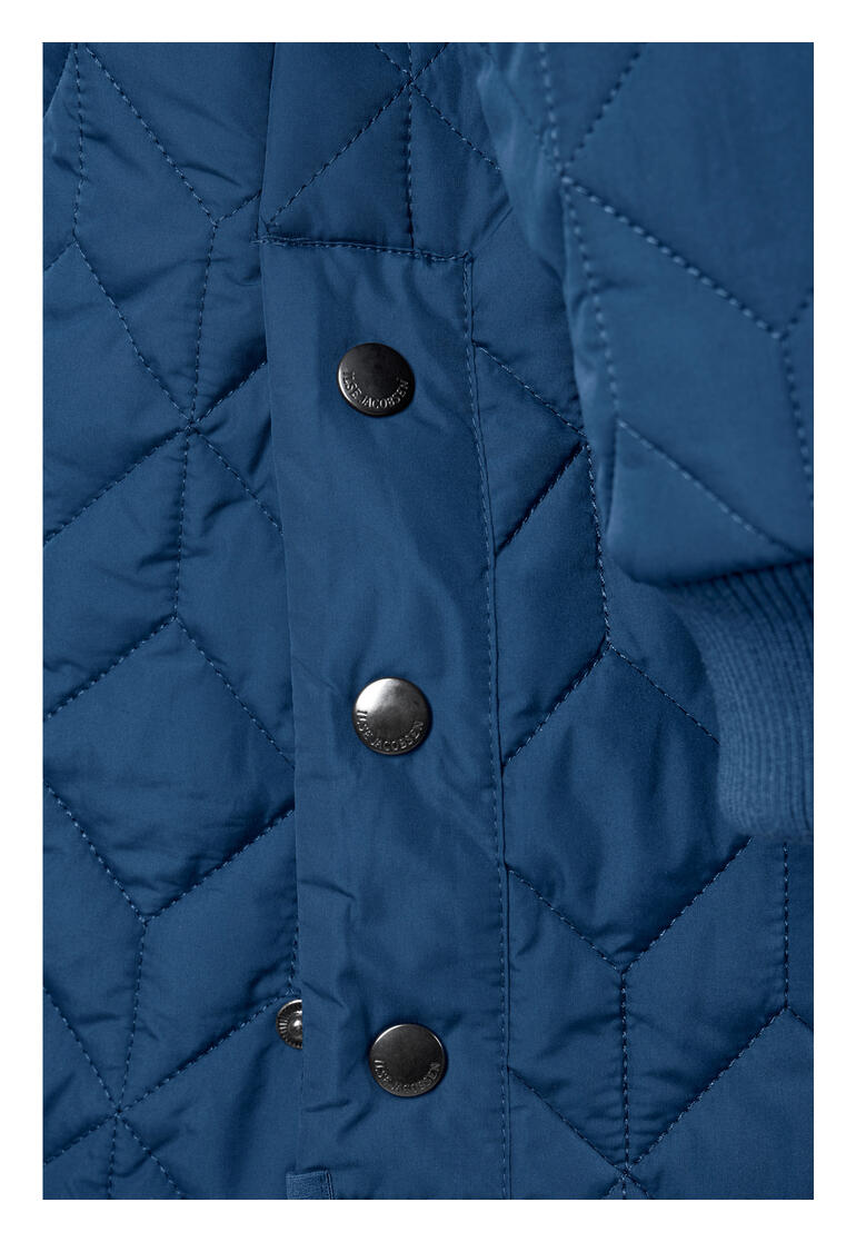 Detailopname van de koningsblauwe gewatteerde jas van Ilse Jacobsen met knopen