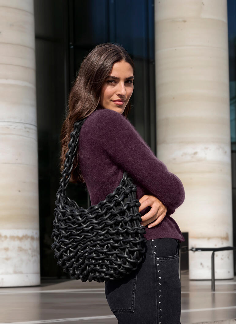 zwart Vrouw draagt een bruine JH1954 cashmere cardigan en houdt een zwarte tas vast
