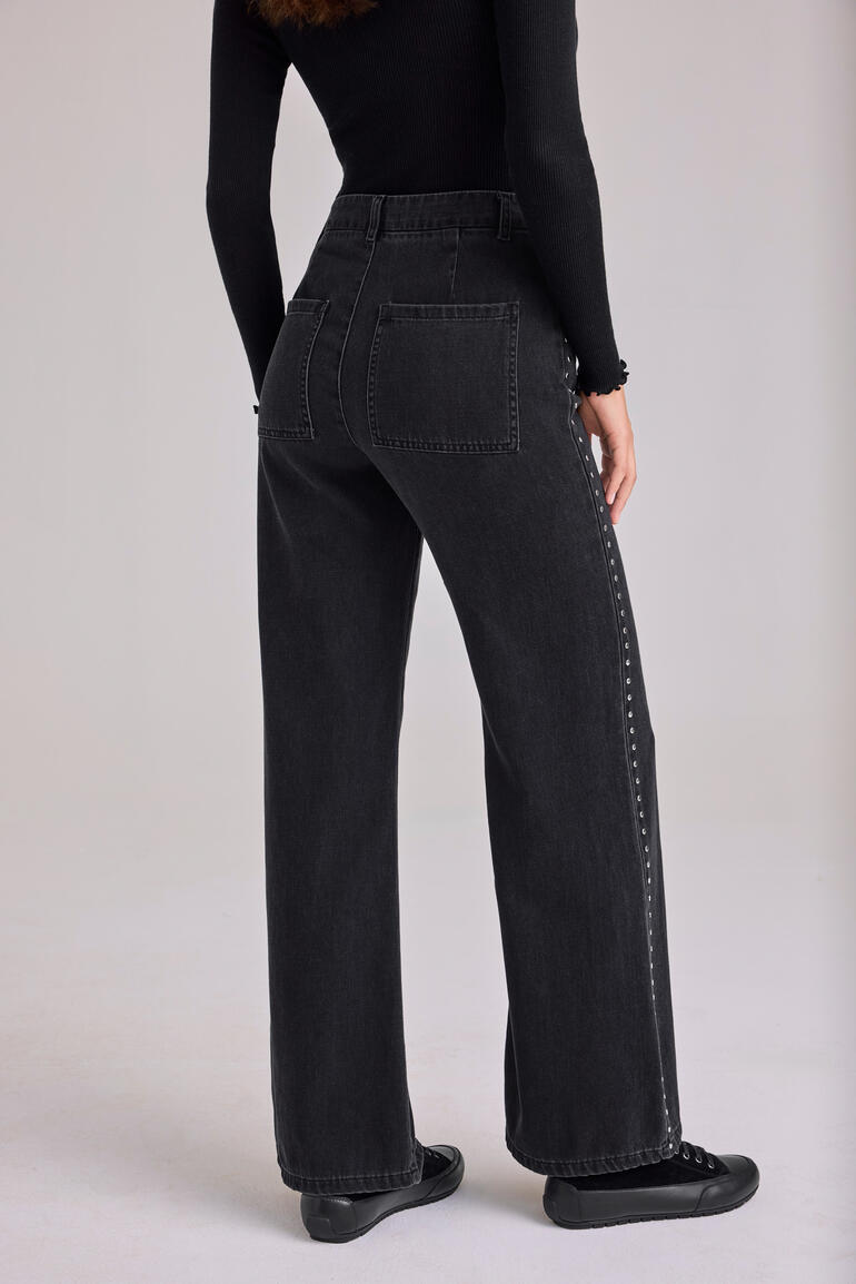 Vrouw draagt zwarte wide-leg jeans met studs van Bella Dahl, achteraanzicht