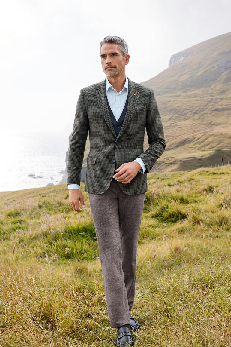 Man in Donegal-sak in een weide bij de zee