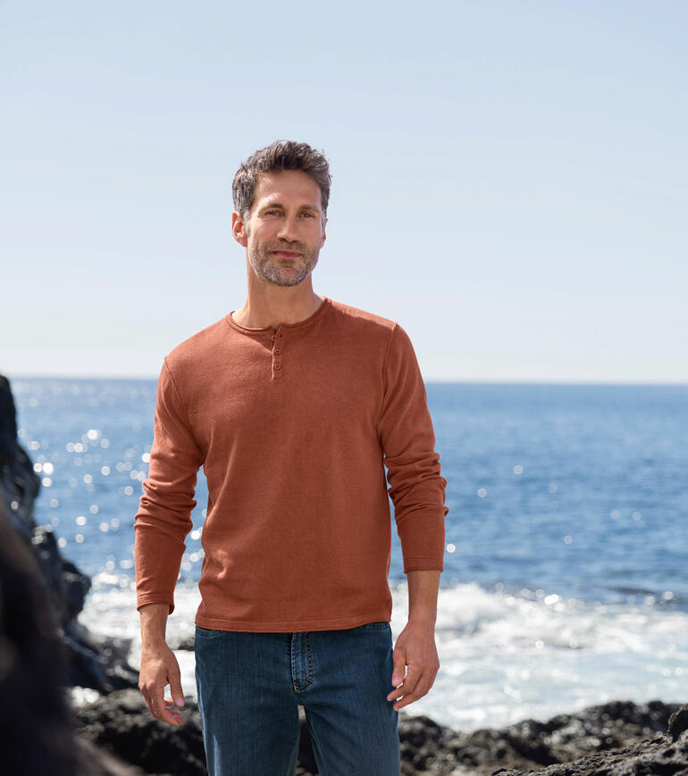 Ragman Casual-pullover Een man staat op het strand in een roestkleurige Ragman trui en jeans.