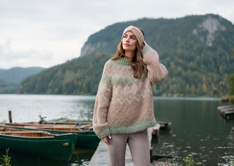 Baestmor Granny-Noorse trui in natuurlijke tinten, gedragen in de open lucht voor een schilderachtige achtergrond.