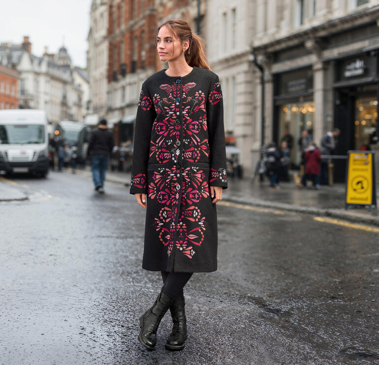 Vrouw draagt IVKO wollen jas met bloemmotief in de stad
