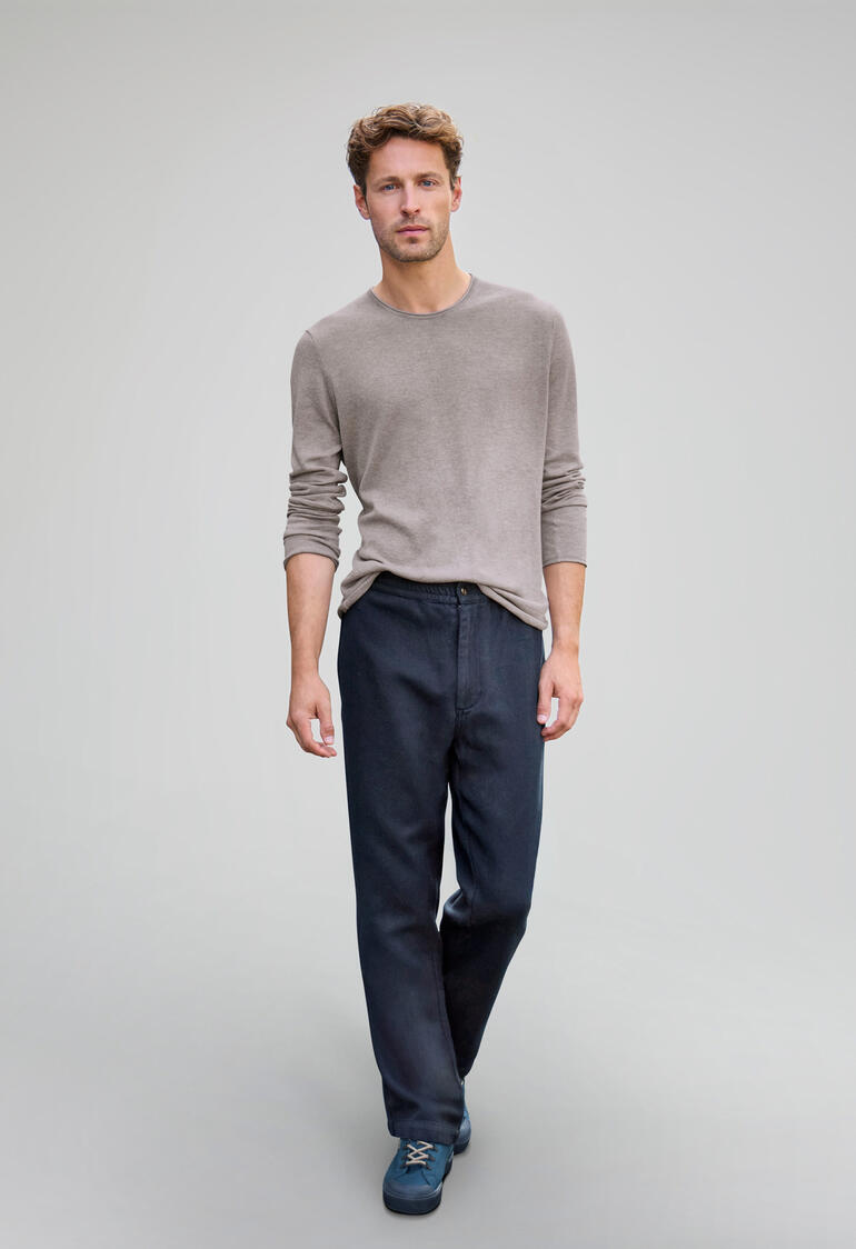 Man in een beige blouse en Navy broek op een grijze achtergrond