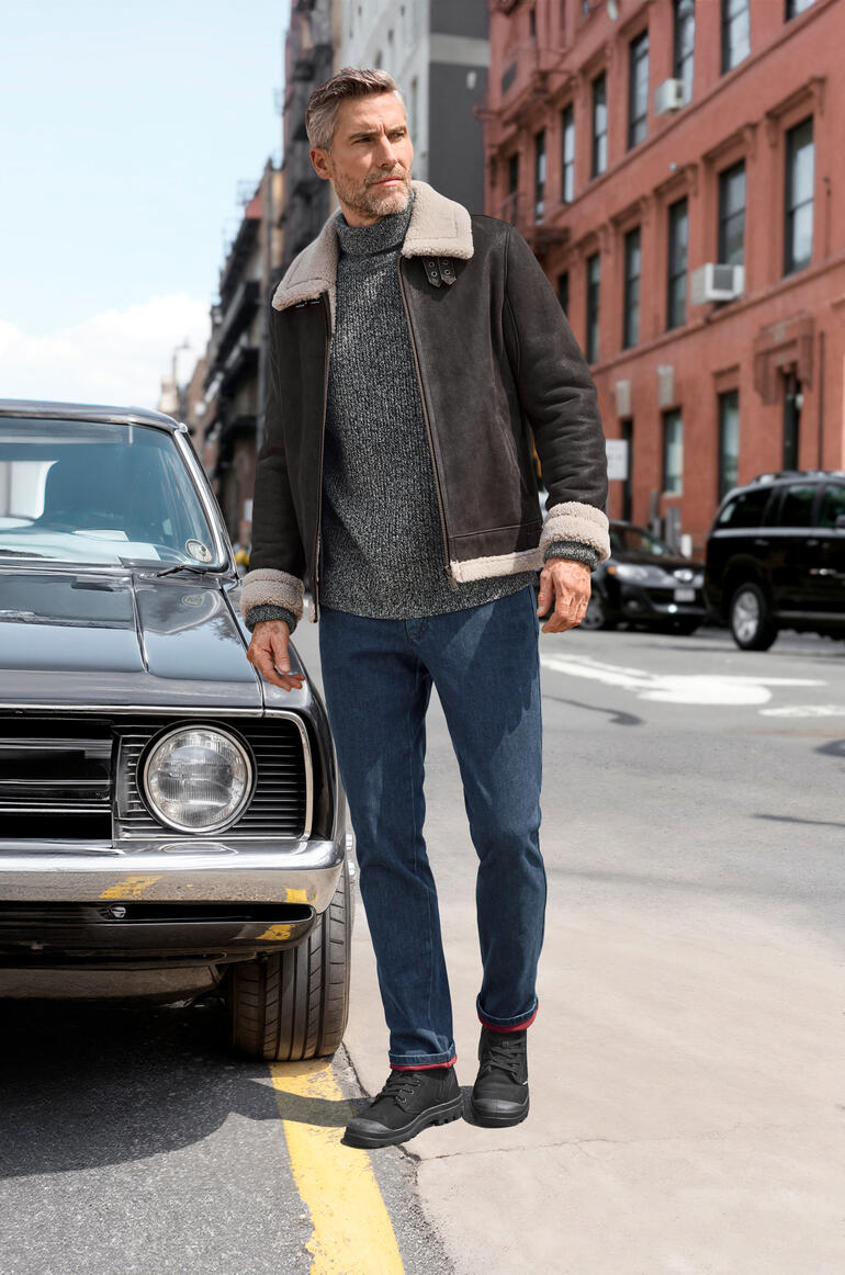 Man in schapenvacht pilotenjack op naast een klassieke auto