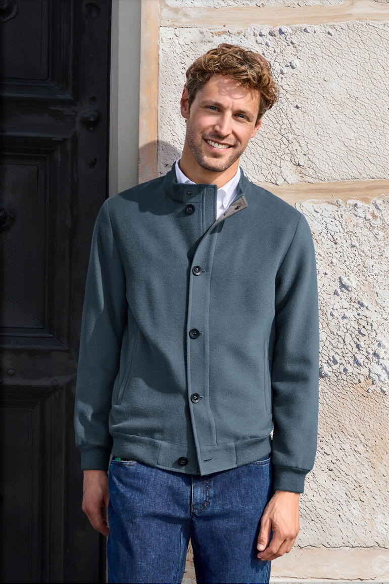 Man draagt een blauwe gebrushte alpaca blouson voor een muur.