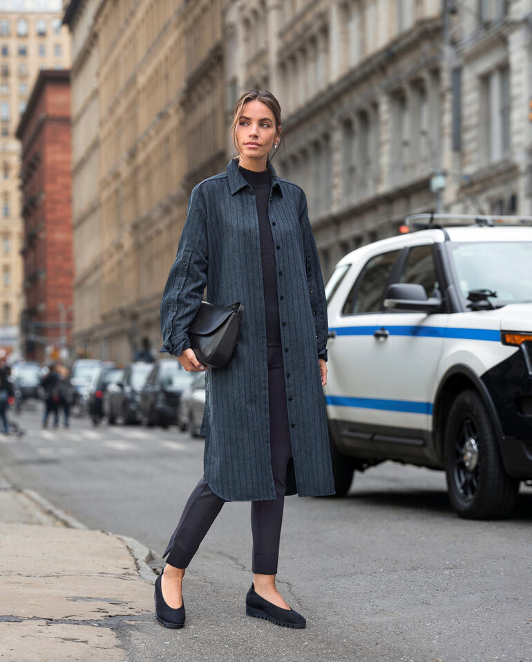 Vrouw in gestreepte lange blouse jurk op straat in de stad.