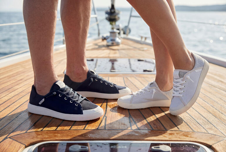 Stel in sneakers staat op een bootvloer.