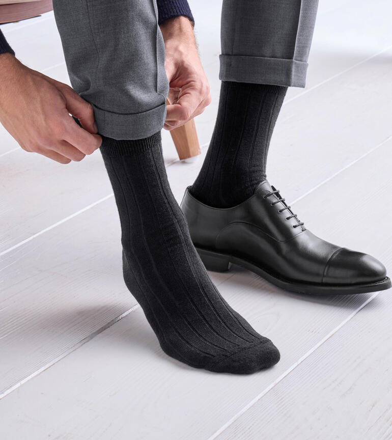 Man trekt grijze alpaca-sokken aan