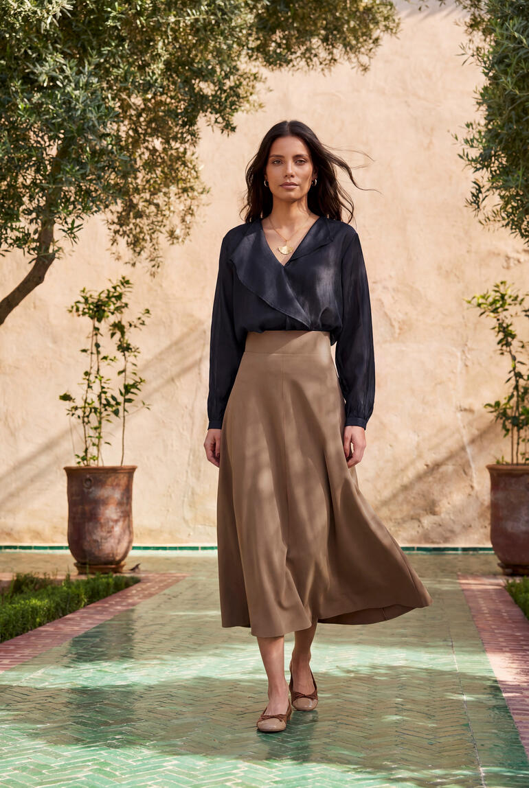 Vrouw in glanzende lyocell-blouse en zwijgende rok
