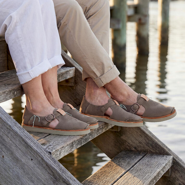 Stel in sneaker-sandalen ontspant op een trap bij het water.