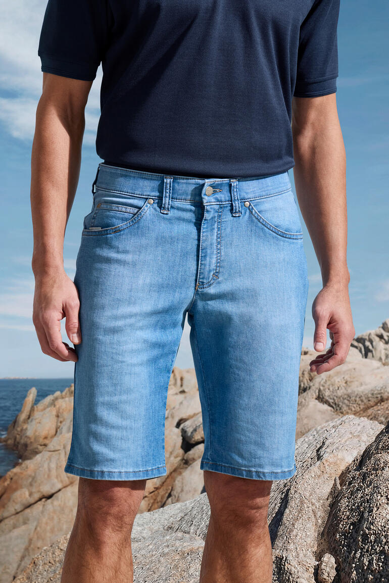 Man in lichte jeans shorts op rotsen in maritieme omgeving