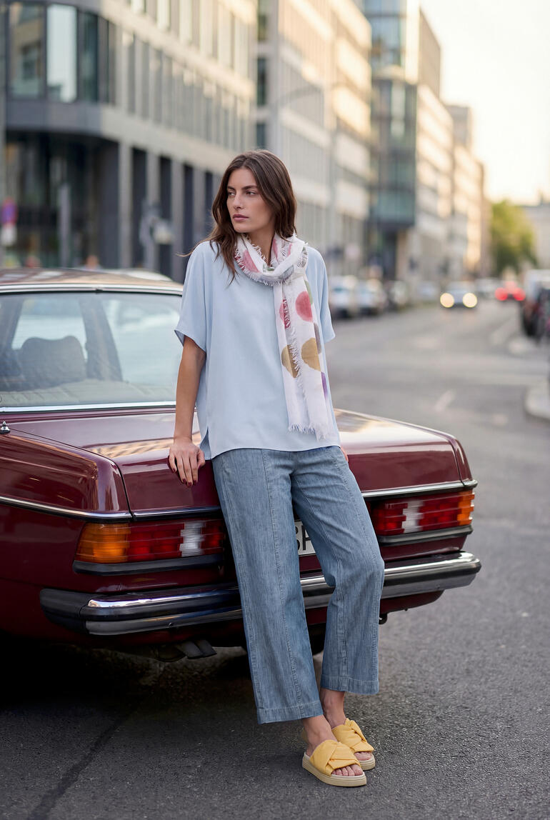 Vrouw in luchtblauw T-shirt en casual outfit naast auto