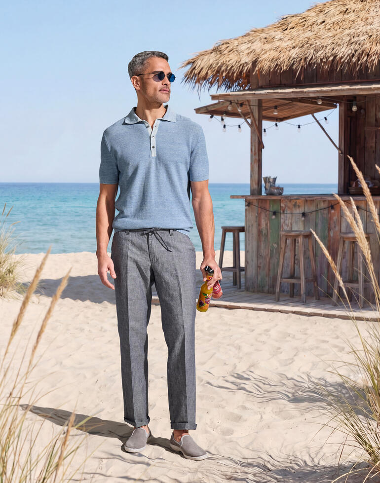 Man in lichtblauw polohemd staat op het strand