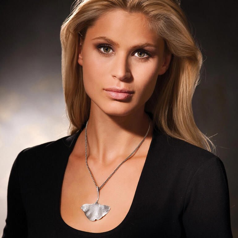 Vrouw draagt een zilveren ginkgo ketting en kijkt opzij.