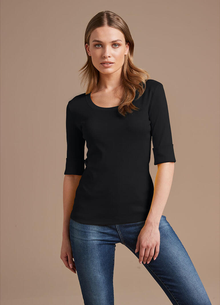 Vrouw in zwart Wolff-shirt met 3/4 mouwen en blauwe jeans.