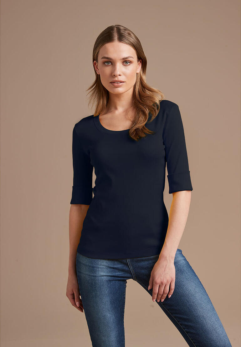Vrouw in zwart Wolff-shirt met 3/4 mouwen en blauwe jeans.