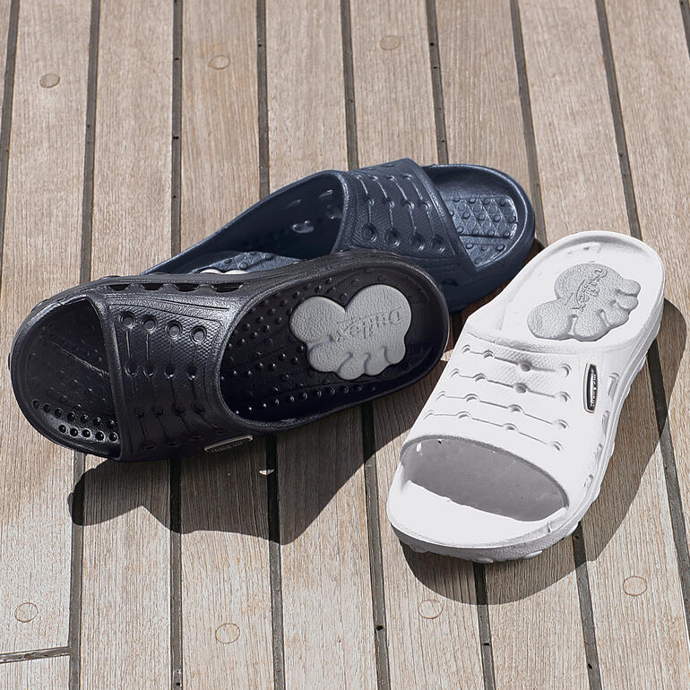 Zwart en blauwe Duxiletten naast elkaar op een houten ondergrond, comfortabele en praktische sandalen.