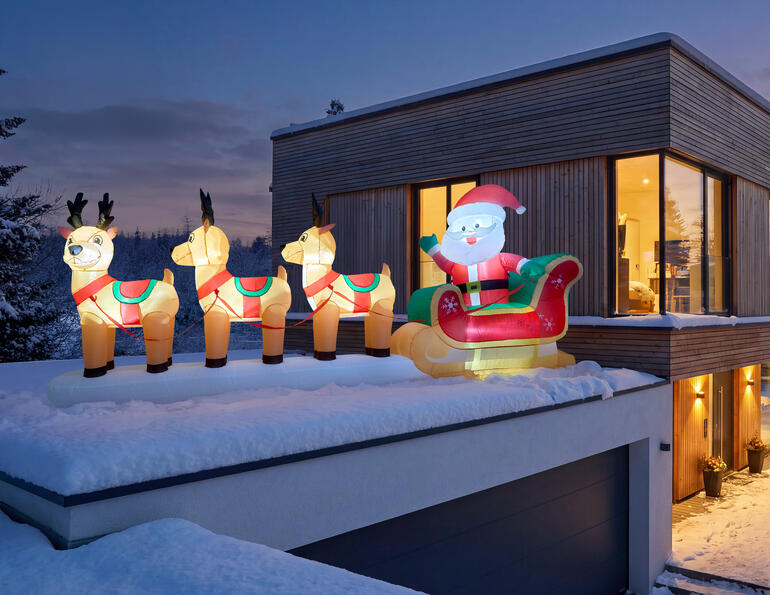 Opblaasbare rendierslee met de Kerstman op het dak van een modern huis.