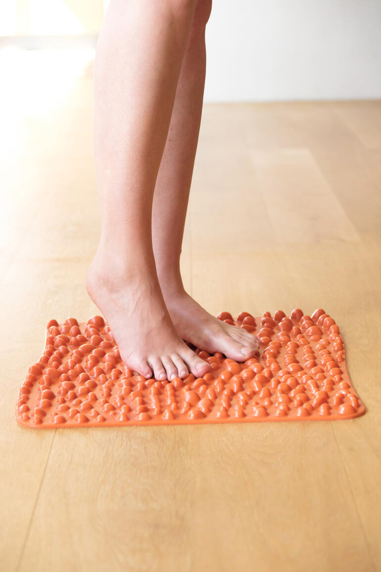 goFit voetreflexmat in feloranje, voeten staan erop.