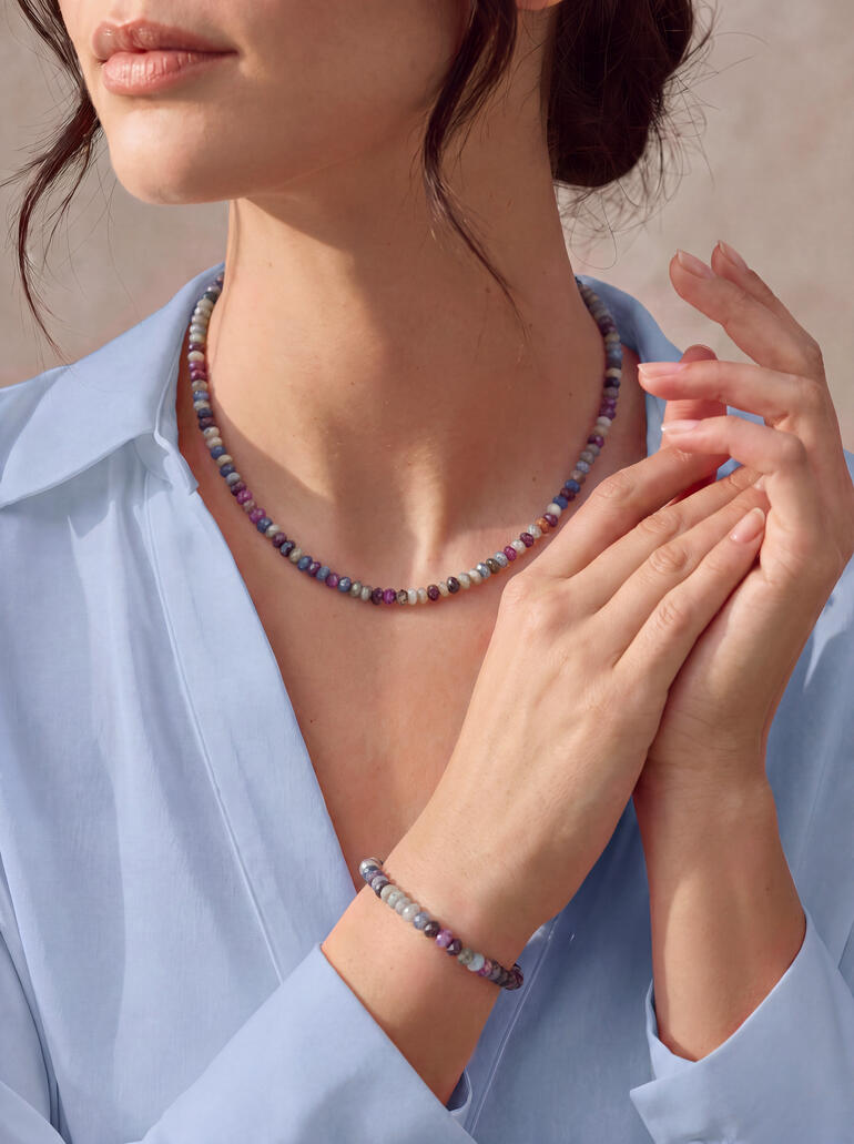 Vrouw draagt een Chamäleon sieradenset met een ketting en armband van kleurrijke kralen.