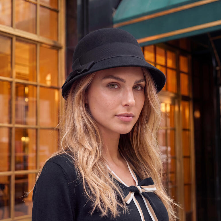 Vrouw in zwarte merino vilten cloche met brede rand