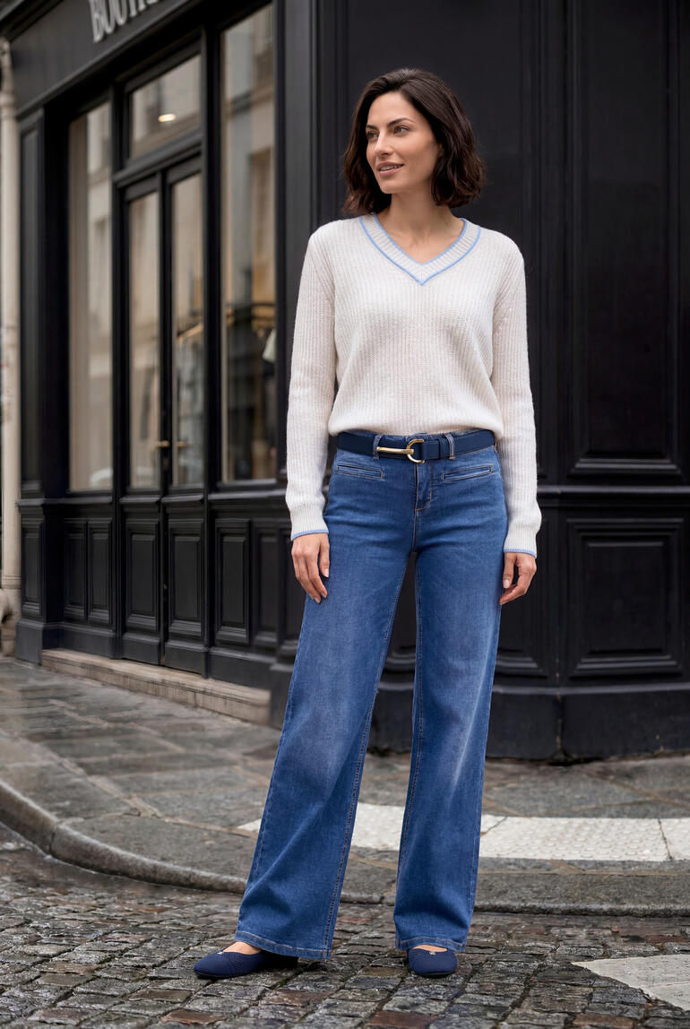 Vrouw in een beige kasjmier-linnen trui en blauwe jeans op een straat