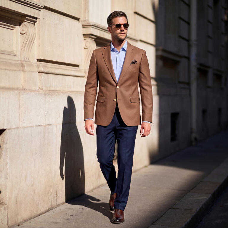 Man in Carl Gross Hopsack blazer loopt door een stadsstraat.