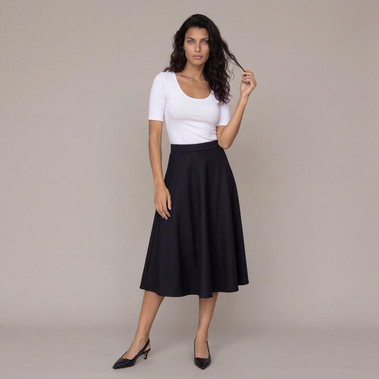 Vrouw in zwarte wollen rok met witte top.