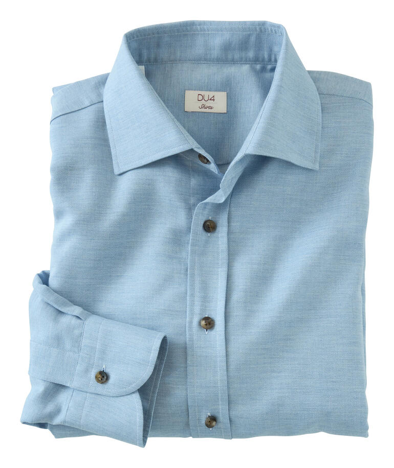 Opgevouwen DU4 kasjmier-flanel shirt in lichtblauw op een tafel.