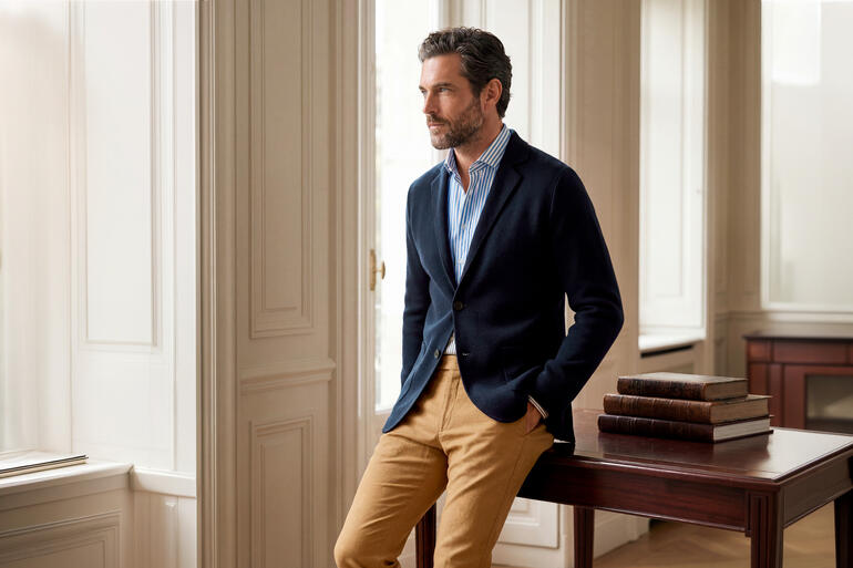 Man in een navy Milano-knit colbert in een elegante ruimte