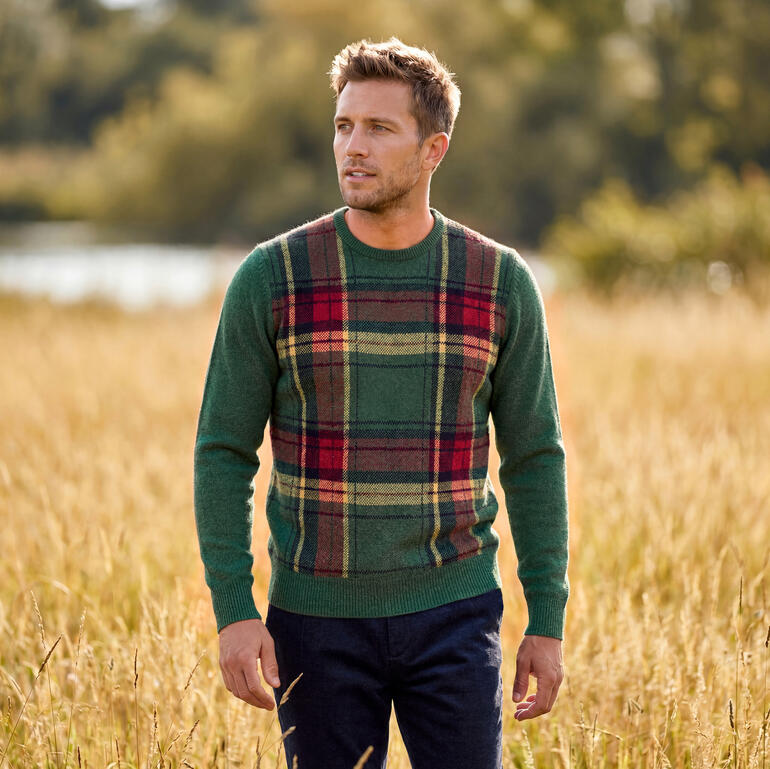Man in tartan trui staat op het veld