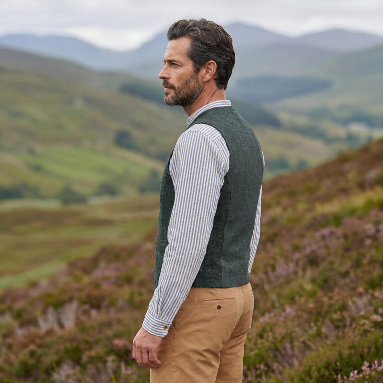 Donkergrijze tweed gilet aan een man in de natuur.