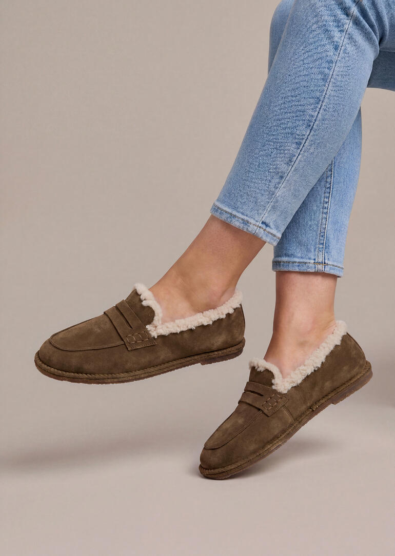 Voeten in bruine lammyloafers, zijaanzicht.
